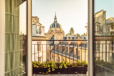 Balcón parisino con flores amarillas y edificios clásicos bajo un cielo cálido al atardecer