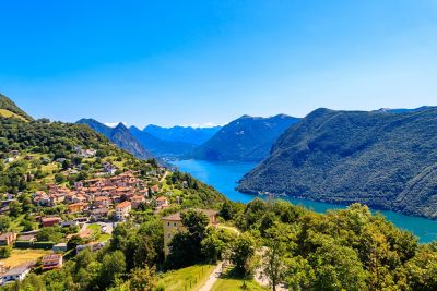 Luganersee mit grünen Bergen vom Monte Brè und Bergdorf Brè im Vordergrund