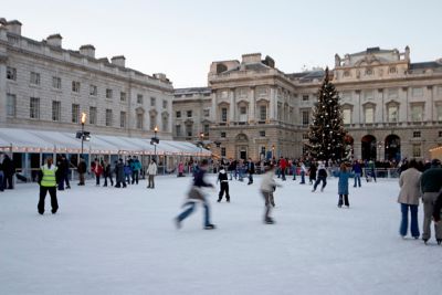 Personas patinando sobre hielo al aire libre en Somerset House con un árbol de Navidad iluminado
