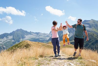 Parents and a laughing young child on a walking holiday in the French Alps