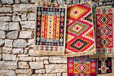 Colourful tapestries hanging against a stone wall in Berat Castle, Albania