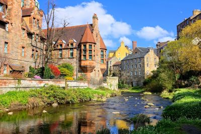 Pueblo medieval de piedra junto a un río sereno bajo un cielo azul despejado