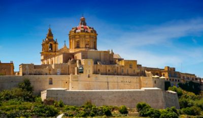 Catedral de Mdina, Malta, con cúpula roja y campanario bajo cielo azul brillante