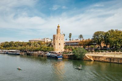 Gente haciendo kayak en el río Guadalquivir, con la torre del Oro al fondo