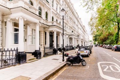 A row of townhouses with colonnaded porticos on a leafy street in Kensington, London