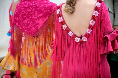 Dos mujeres de espaldas, vestidas con trajes de flamenca