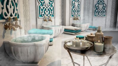 Interior of a hammam spa with marble sinks and gold taps in calming shades of white, grey and turquoise