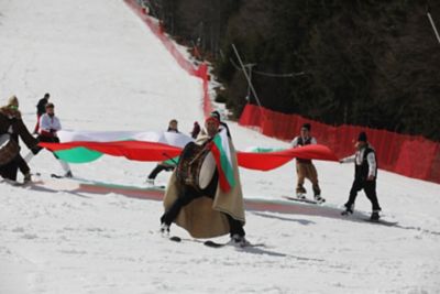 Skiers in traditional Bulgarian clothing with flags at Pamporovo ski resort