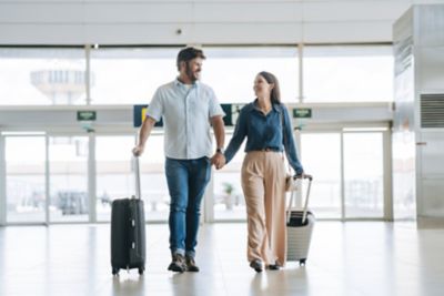 A happy couple holding hands as they stroll through an airport