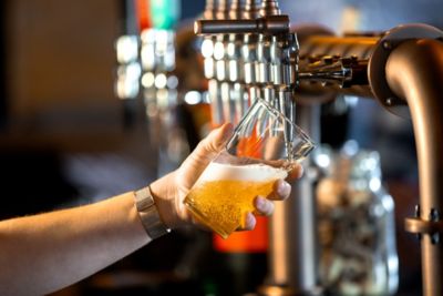 A pint of golden lager being pulled at a traditional pub in England