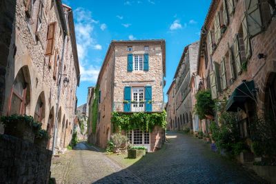 Ruelles pavées de Cordes-sur-Ciel bordées de maisons anciennes, avec au centre une maison aux volets bleus