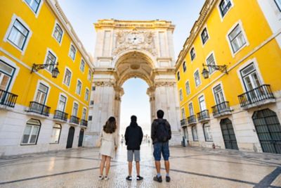 Trois digital nomads visitent Lisbonne et admirent l'Arc de triomphe depuis la Rua Augusta