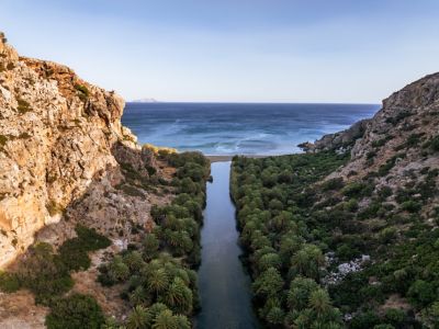 Von Palmen und Felsen gesäumte Flussmündung am Preveli Beach auf Kreta