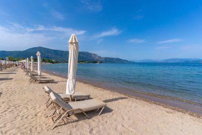 Dassia Beach in Corfu, with sun loungers and umbrellas on powder sand facing the Ionian Sea