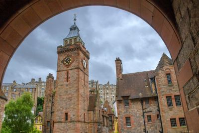Torre del reloj de piedra rojiza en Dean Village, enmarcada por un arco de medio punto