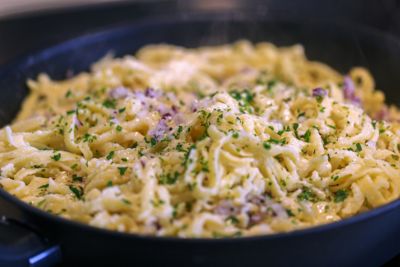 Schwäbische Kässpätzle mit Zwiebeln und Kräutern in einer Pfanne