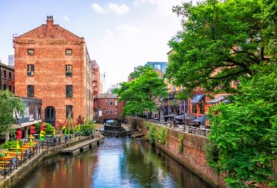 Canal de Mánchester bordeado por edificios industriales de ladrillo rojo, árboles y banderas