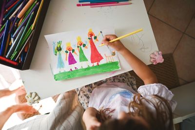 A child drawing a colourful picture of a smiling family