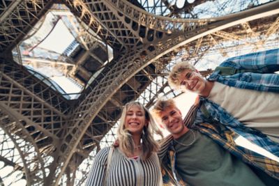 Smiling teenagers under the wrought-iron arches of the Eiffel Tower in Paris