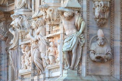 Intricately carved statues in white marble on the façade of Milan Cathedral