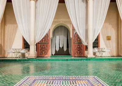 The calm courtyard of Le Jardin Secret in Marrakech, with white curtains and an arched doorway