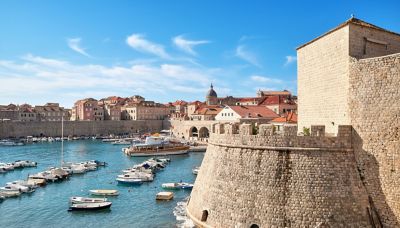 Boats moored in the port next to Dubrovnik's stone city walls and ramparts
