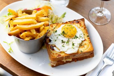 Croque madame accompagné de frites, servi dans un bistrot parisien