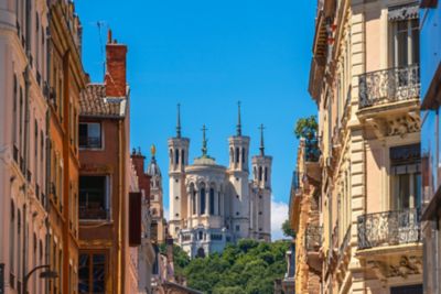 Basílica blanca con torres puntiagudas entre edificios clásicos bajo un cielo azul despejado