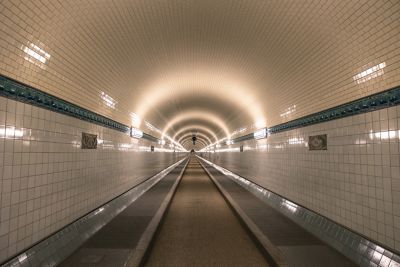 Menschenleerer, weiß gefliester Alter Elbtunnel Hamburg im Neonlicht