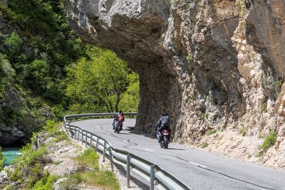 Motorcyclists winding under a limestone cliff in Gorges du Loup near Nice, France