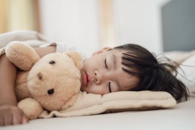 A child sleeping peacefully while cuddling a teddy