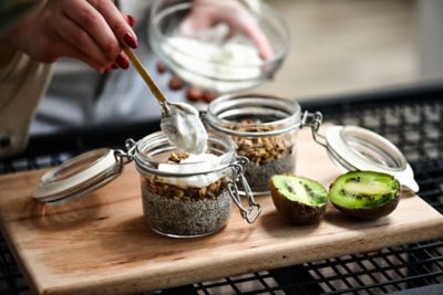 A nutritious snack of chia pudding, granola and fresh kiwi being prepared
