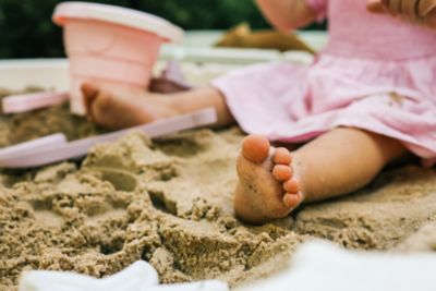 A preschooler in a sandpit, engaged in sensory play
