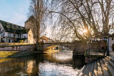 A golden sunset illuminating a quaint footbridge over the Ill River, Alsace
