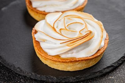 Runde, kleine Tarte au Citron mit rosenförmigem Baiser, ein beliebtes französisches Dessert