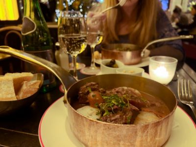 Bœuf bourguignon servi dans une cassolette, dans un bistrot parisien rempli de clients