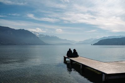 Un couple, emmitouflé dans des manteaux, apprécie une pause romantique sur un ponton du lac d’Annecy