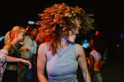 A young person with striking curly hair dancing in a nightclub