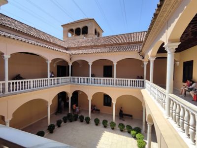 Visitors sitting on benches in the courtyard of the Picasso Museum in Málaga, Spain