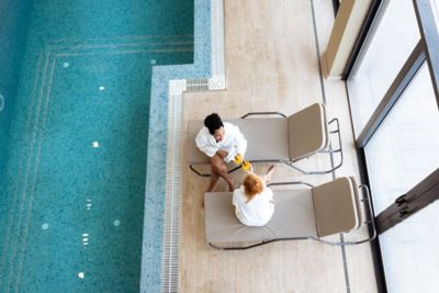 A pair of wellness seekers at a luxury spa resort, chatting by the indoor pool