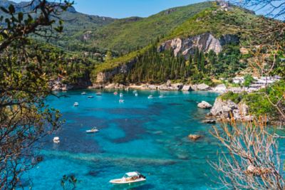 Die Bucht von Liapades auf Korfu mit kleinen Booten in türkisblauem Wasser vor grünen Hügeln