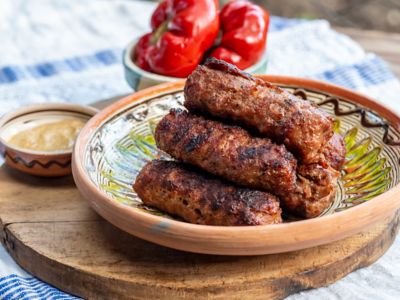 Horezu-Keramikschale mit Mici, rumänischen Würsten, dazu Senf und eingelegte rote Paprika