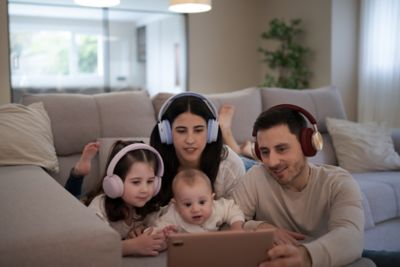 A family in their living room wearing headphones and focused on a tablet