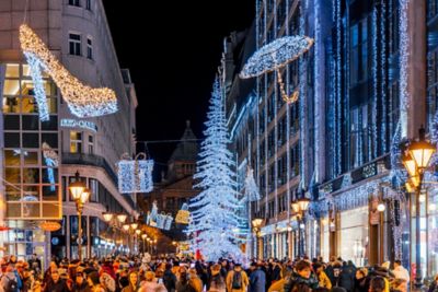 Calle concurrida de Budapest con luces navideñas, árbol iluminado y decoraciones festivas