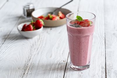A strawberry smoothie garnished with mint and chia seeds, an ideal hot weather recipe