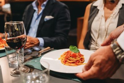 Elegantly plated spaghetti being served at a fine dining Italian restaurant