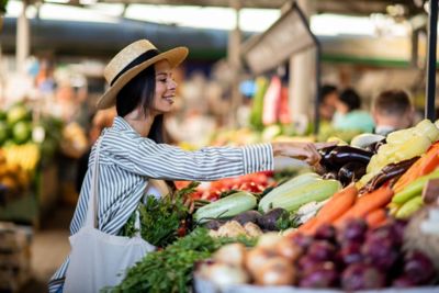 A shopper at a farmers' market choosing fresh, colourful vegetables