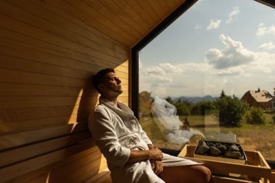 A wellness seeker relaxing in a sauna overlooking the countryside