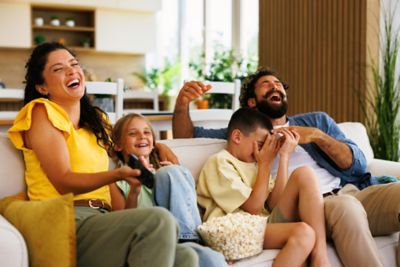 A family laughing as they watch a film, a great holiday preparation activity