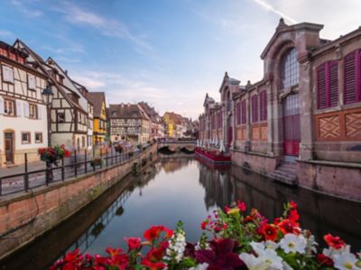 Quartier historique de la Petite Venise à Colmar au coucher du soleil, avec maisons à colombages colorées, fleurs et marché couvert